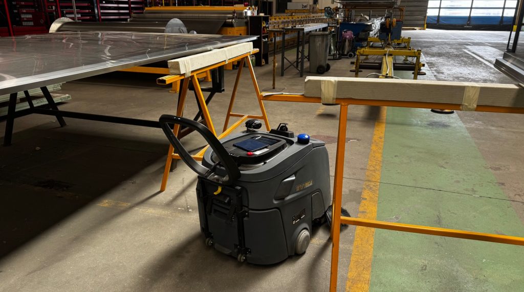 Robot de nettoyage autonome en test dans un entrepôt logistique avec équipes sur le terrain